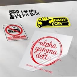A collection of custom transfer stickers featuring various designs and colours on a light marble surface.