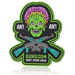 A custom PVC patch featuring a colourful skull with a brain, surrounded by crossed rifles. Bright green, pink, and black colours are used.