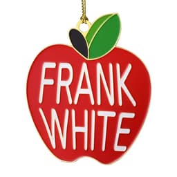 A red apple-shaped ornament featuring the name "FRANK WHITE" in white letters and a green leaf, with a gold chain.