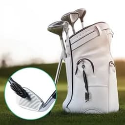 A white golf bag with a brush for cleaning club grooves, alongside several golf clubs, set against a grassy background.