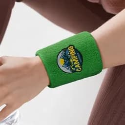 A green terry sweatband wristband with a woven logo, resting on a person's wrist.