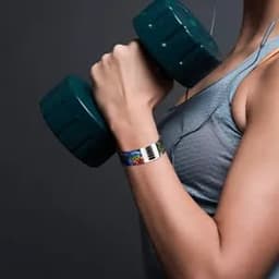 A female athlete holding a green dumbbell, wearing a multicoloured Tyvek paper bracelet on her wrist.