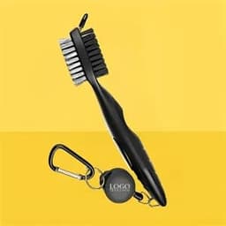A black golf club brush and groove cleaner with a carabiner attachment, set against a yellow background.