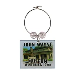 A wine charm featuring a rectangular design with an image of a museum and a logo. It has a silver ring and pink beads.