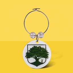 A wine charm featuring a circular white pendant with a green tree design and a silver hoop.