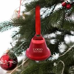 A red holiday bell ornament with a ribbon, hanging on a Christmas tree alongside a shiny red bauble.