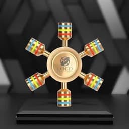 A gold hexagonal fidget spinner with colourful detachable sections, displayed on a black pedestal with a logo.