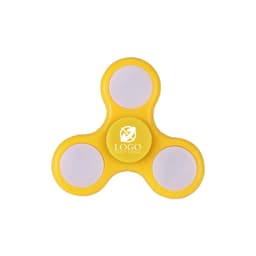 A yellow fidget spinner with three white surfaces and a central logo. It's a novelty item with LED lights.
