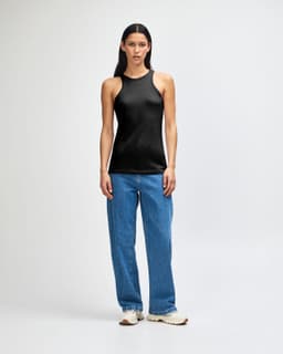 A black racerneck tank top with a fitted design, worn with light blue cargo pants and styled with black and white sneakers.