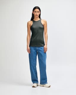A woman wearing a dark green American Apparel CVC racerneck tank top paired with light blue cargo pants.