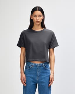 A grey women's boxy t-shirt with short sleeves, featuring a round neckline and a logo on the side.