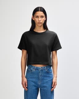 A black women's boxy t-shirt displayed on a model, featuring a relaxed fit and short sleeves.