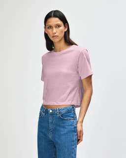 A pink women's boxy t-shirt with a relaxed fit, featuring a logo, styled with denim jeans.