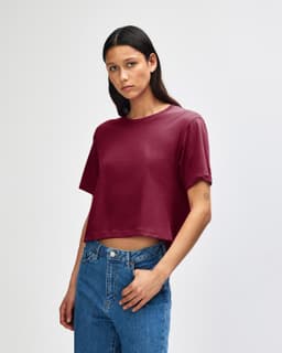 A maroon women's fine jersey boxy t-shirt displayed on a model with curly hair, featuring a casual fit.