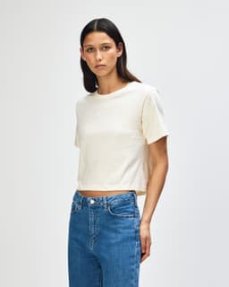 A women's fine jersey boxy t-shirt in cream, paired with light blue jeans, featuring a branding logo.