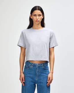 A grey women's boxy t-shirt with short sleeves, displayed on a model. The shirt has a logo.