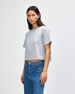 A grey women's fine jersey boxy T-shirt, featuring short sleeves and a cropped design, displayed on a model in profile.
