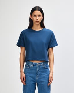 A navy women's fine jersey boxy T-shirt featured on a model, paired with light blue jeans. The shirt has a logo.