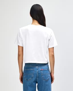 A white women's boxy t-shirt from American Apparel, featuring a plain back, paired with denim jeans.
