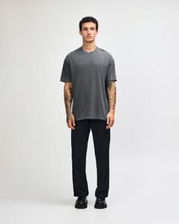 A model wearing a grey heavyweight cotton t-shirt paired with olive green cargo pants. The shirt has a logo.