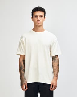 An unisex heavyweight cotton T-shirt in a light cream colour, featuring a simple design and a logo.