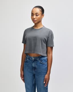A grey cropped boxy t-shirt for women, featuring a relaxed fit and short sleeves. It has a logo on it.
