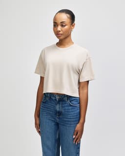 A heavyweight cotton women's crop boxy T-shirt in a neutral beige colour, featuring a relaxed fit and a branding logo.