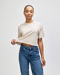 A heavyweight cotton women's crop boxy t-shirt in a neutral beige colour, featuring a round neckline and short sleeves.
