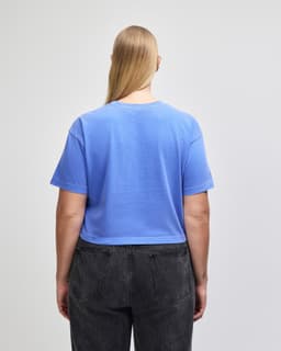 A back view of a women's royal blue crop boxy t-shirt, paired with high-waisted denim jeans.