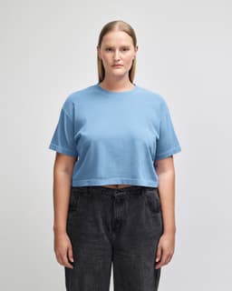 A blue cropped boxy t-shirt made from heavyweight cotton, featuring a logo on the fabric.