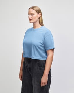 A blue heavyweight cotton women's crop boxy T-shirt with a loose fit, featuring a logo on the side.