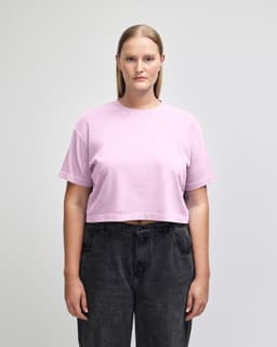 A pink heavyweight cotton women's garment dyed crop boxy t-shirt, paired with blue jeans, featuring a logo.