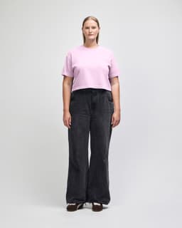 A pink cropped boxy T-shirt paired with light blue high-waisted jeans, modelled by a woman. The outfit has a casual look.