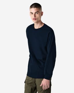 A long sleeve unisex t-shirt in navy blue, featuring a logo and styled with khaki pants.