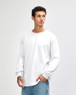 A white heavyweight cotton unisex long sleeve T-shirt displayed on a model, featuring a simple design and branding.