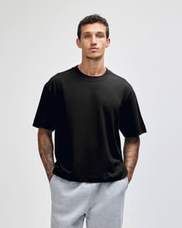 A black heavyweight cotton unisex boxy t-shirt worn by a model, paired with grey sweatpants.