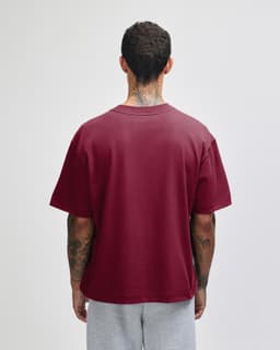 A maroon unisex boxy t-shirt viewed from the back, with a simple design and short sleeves.