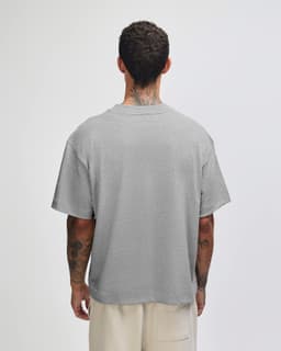 A grey unisex boxy T-shirt displayed from the back, featuring short sleeves and a relaxed fit.