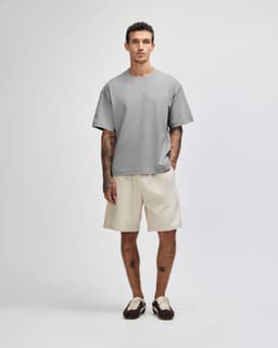 A model wearing a grey heavyweight cotton unisex boxy t-shirt paired with black wide-legged pants.