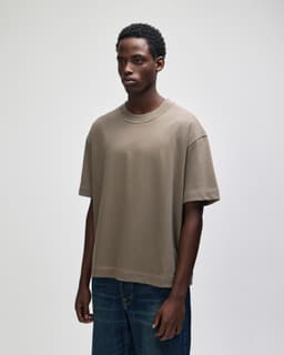 A unisex boxy t-shirt in a muted brown shade, featuring a relaxed fit and a logo on the sleeve.