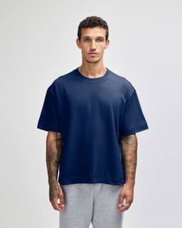 A navy unisex boxy T-shirt with short sleeves, paired with grey bottoms, featuring a branding logo.