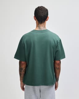 A green heavyweight cotton unisex boxy T-shirt viewed from the back, featuring a casual fit.