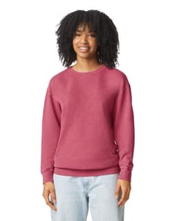 A woman is wearing a lightweight crewneck sweatshirt in a deep maroon colour. The sweatshirt has a logo.