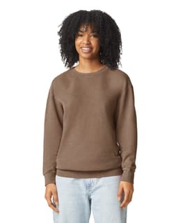A brown crewneck sweatshirt featuring a relaxed fit. The model has curly hair and is smiling. The sweatshirt has a logo.