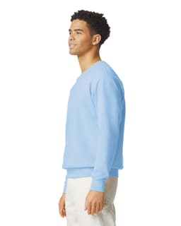 A light blue crewneck sweatshirt is displayed on a model, featuring a simple design and a logo.