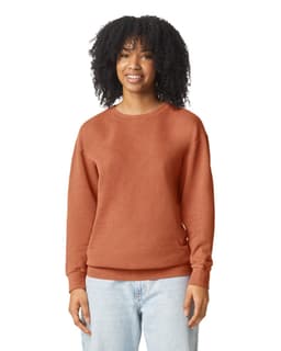 A woman wears an orange-brown lightweight crewneck sweatshirt, featuring a relaxed fit and long sleeves.