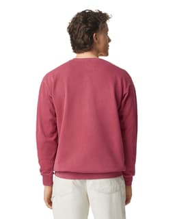 A crewneck sweatshirt in a deep pink shade, featuring a simple design and ribbed cuffs at the wrists.
