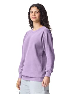 A purple adult crewneck sweatshirt featuring long sleeves and ribbed cuffs, displayed on a model.