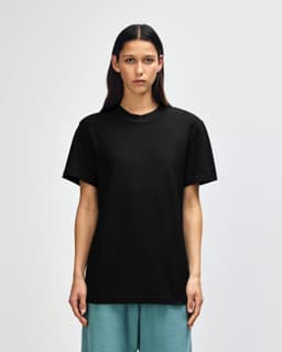 A black unisex pique mockneck T-shirt displayed on a model, featuring a logo on the garment.