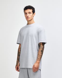 A grey unisex pique mockneck T-shirt with short sleeves, featuring a side view of the model wearing it.